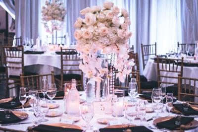 Un couple marche dans un champ au coucher du soleil, la femme portant une robe blanche et tenant légèrement son ourlet.