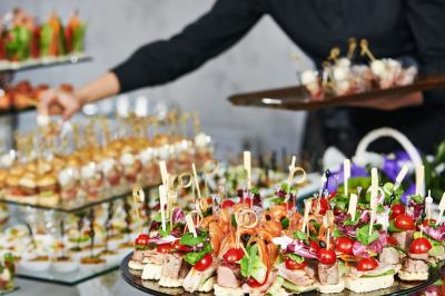 Un couple marche dans un champ au coucher du soleil, la femme portant une robe blanche et tenant légèrement son ourlet.