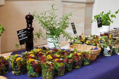 Un couple marche dans un champ au coucher du soleil, la femme portant une robe blanche et tenant légèrement son ourlet.
