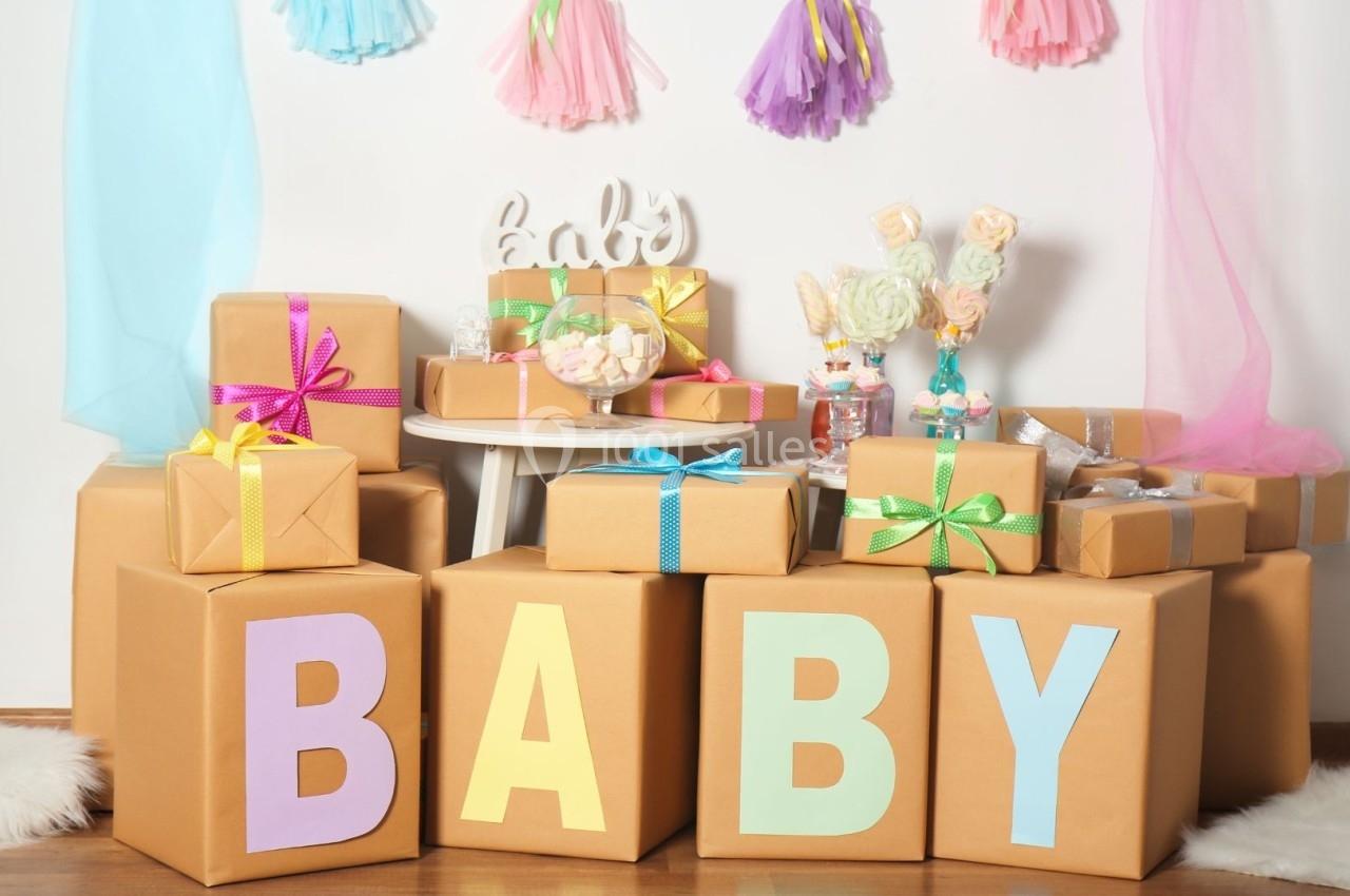 Cadeaux emballés avec des rubans colorés et décorations de fête sur le thème de bébé dans un décor festif.