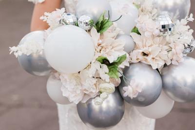 Un couple marche dans un champ au coucher du soleil, la femme portant une robe blanche et tenant légèrement son ourlet.
