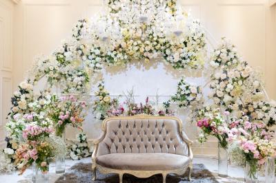 Un couple marche dans un champ au coucher du soleil, la femme portant une robe blanche et tenant légèrement son ourlet.