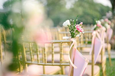 Un couple marche dans un champ au coucher du soleil, la femme portant une robe blanche et tenant légèrement son ourlet.