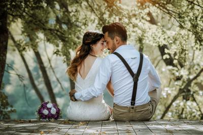 Un couple marche dans un champ au coucher du soleil, la femme portant une robe blanche et tenant légèrement son ourlet.