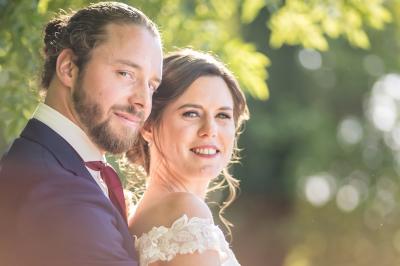 Femme en robe blanche souriante, assise près d'une fontaine, avec un homme en costume visible de dos.