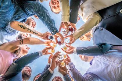 Femme en robe blanche souriante, assise près d'une fontaine, avec un homme en costume visible de dos.