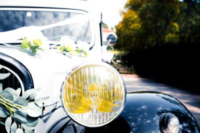 Femme en robe blanche souriante, assise près d'une fontaine, avec un homme en costume visible de dos.