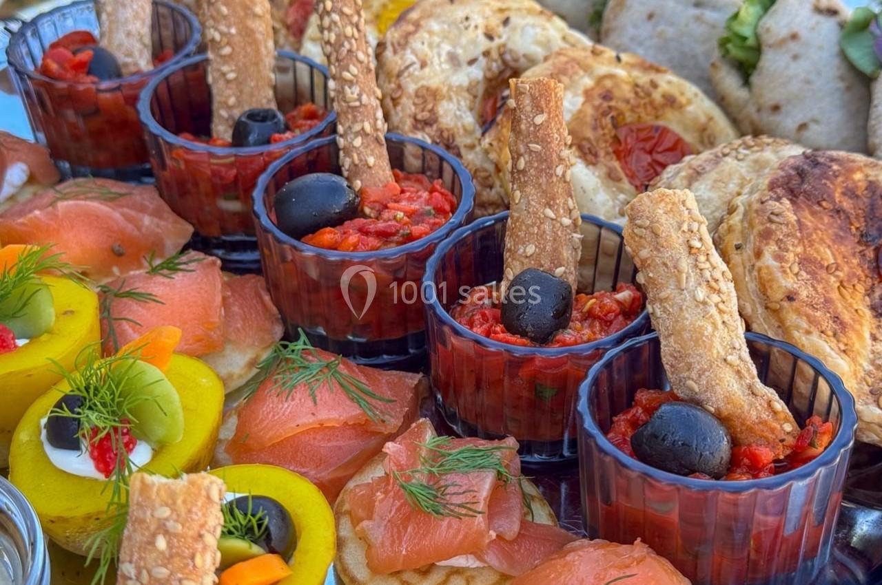 Assortiment de tapas avec saumon fumé, légumes, pains variés et verrines garnies d'olives et de tartinades.