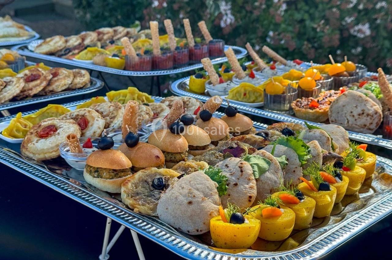 Plateaux garnis de mini-sandwichs, wraps, verrines et amuse-bouches variés présentés en extérieur.