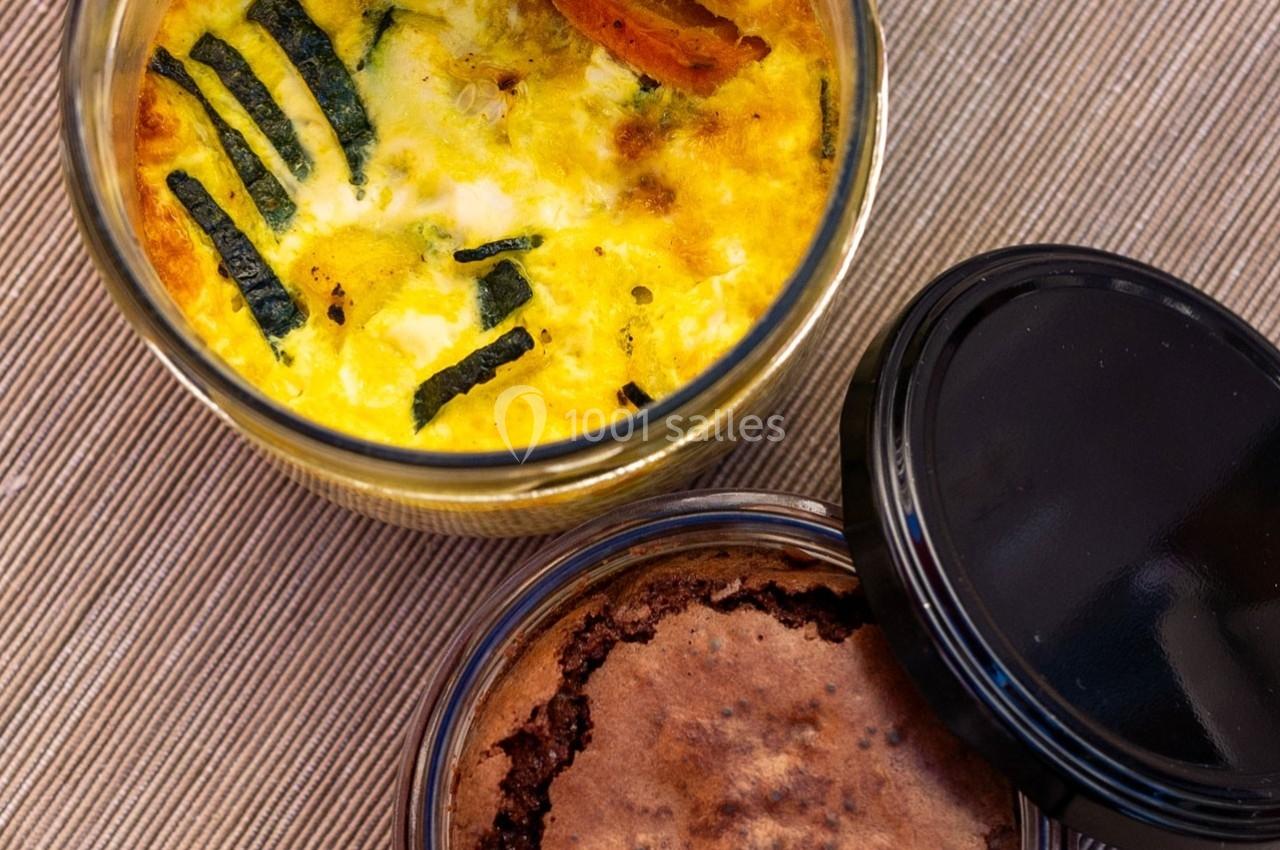 Quiche aux légumes et dessert au chocolat dans des bocaux en verre, posés sur une nappe beige.