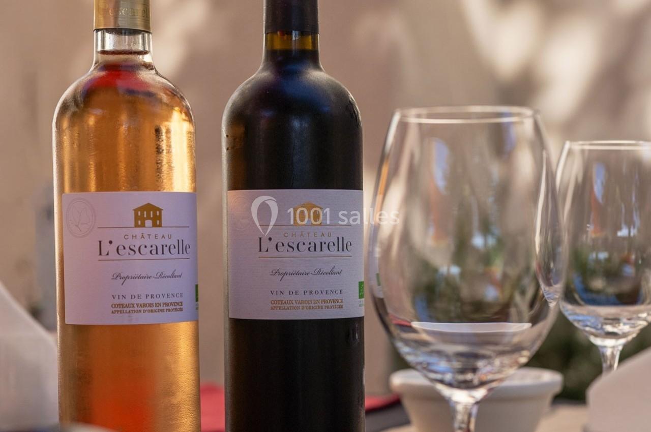 Deux bouteilles de vin Château L'Escarelle, rouge et rosé, posées sur une table avec des verres à vin vides.