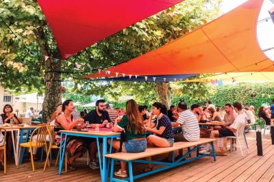 Mur en pierre orné d'une mosaïque colorée représentant un motif circulaire, entouré de végétation.