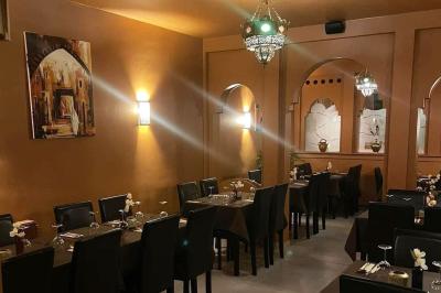 Un groupe d'hommes en tenues traditionnelles pose devant une décoration orientale et une affiche promotionnelle.