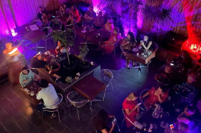 Un groupe d'hommes en tenues traditionnelles pose devant une décoration orientale et une affiche promotionnelle.