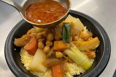 Un groupe d'hommes en tenues traditionnelles pose devant une décoration orientale et une affiche promotionnelle.