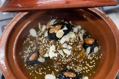 Un groupe d'hommes en tenues traditionnelles pose devant une décoration orientale et une affiche promotionnelle.
