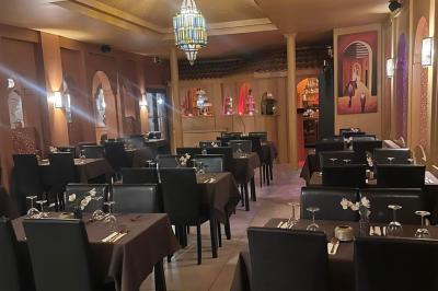 Un groupe d'hommes en tenues traditionnelles pose devant une décoration orientale et une affiche promotionnelle.