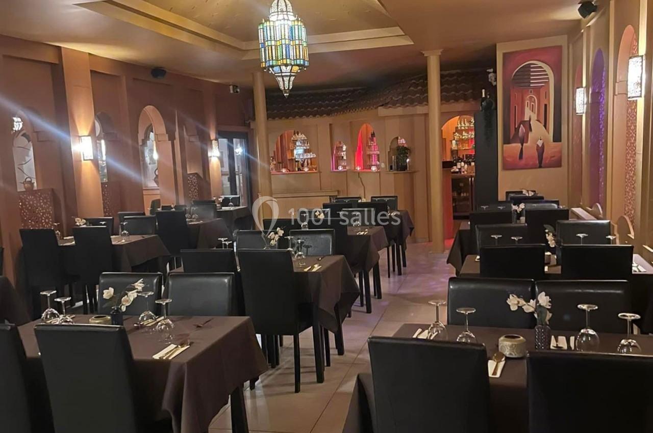 Salle de restaurant décorée dans un style oriental, avec tables dressées et éclairage chaleureux.