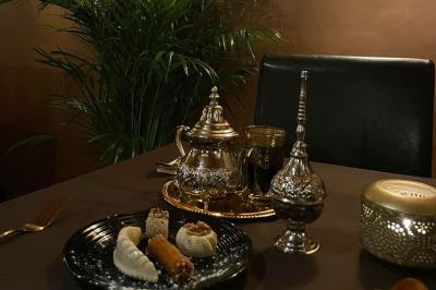 Un groupe d'hommes en tenues traditionnelles pose devant une décoration orientale et une affiche promotionnelle.