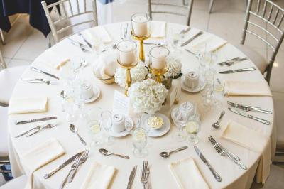 Bougies allumées et fleurs blanches disposées sur une table décorée pour un événement dans une ambiance tamisée.