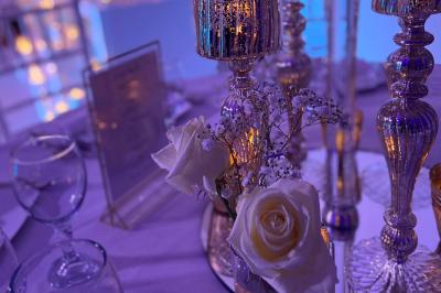 Bougies allumées et fleurs blanches disposées sur une table décorée pour un événement dans une ambiance tamisée.