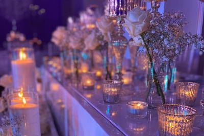Bougies allumées et fleurs blanches disposées sur une table décorée pour un événement dans une ambiance tamisée.