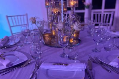 Bougies allumées et fleurs blanches disposées sur une table décorée pour un événement dans une ambiance tamisée.