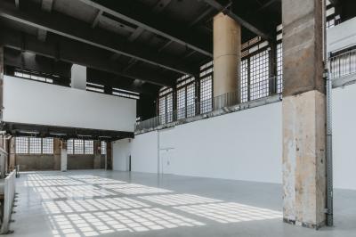 Vue d'un parking vide en extérieur, entouré de bâtiments modernes sous un ciel partiellement nuageux.