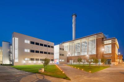 Vue d'un parking vide en extérieur, entouré de bâtiments modernes sous un ciel partiellement nuageux.