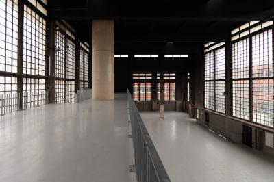 Vue d'un parking vide en extérieur, entouré de bâtiments modernes sous un ciel partiellement nuageux.