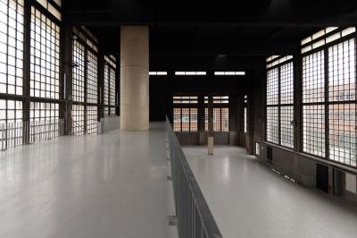 Vue d'un parking vide en extérieur, entouré de bâtiments modernes sous un ciel partiellement nuageux.