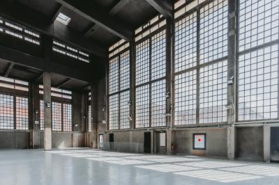 Vue d'un parking vide en extérieur, entouré de bâtiments modernes sous un ciel partiellement nuageux.