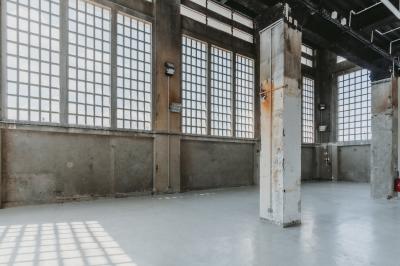 Vue d'un parking vide en extérieur, entouré de bâtiments modernes sous un ciel partiellement nuageux.