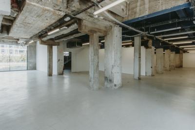 Vue d'un parking vide en extérieur, entouré de bâtiments modernes sous un ciel partiellement nuageux.