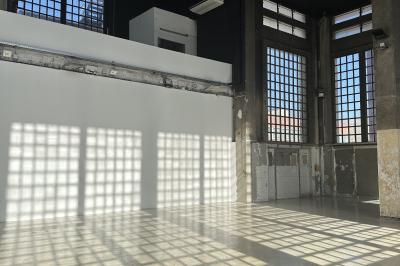 Vue d'un parking vide en extérieur, entouré de bâtiments modernes sous un ciel partiellement nuageux.