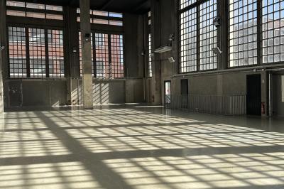 Vue d'un parking vide en extérieur, entouré de bâtiments modernes sous un ciel partiellement nuageux.