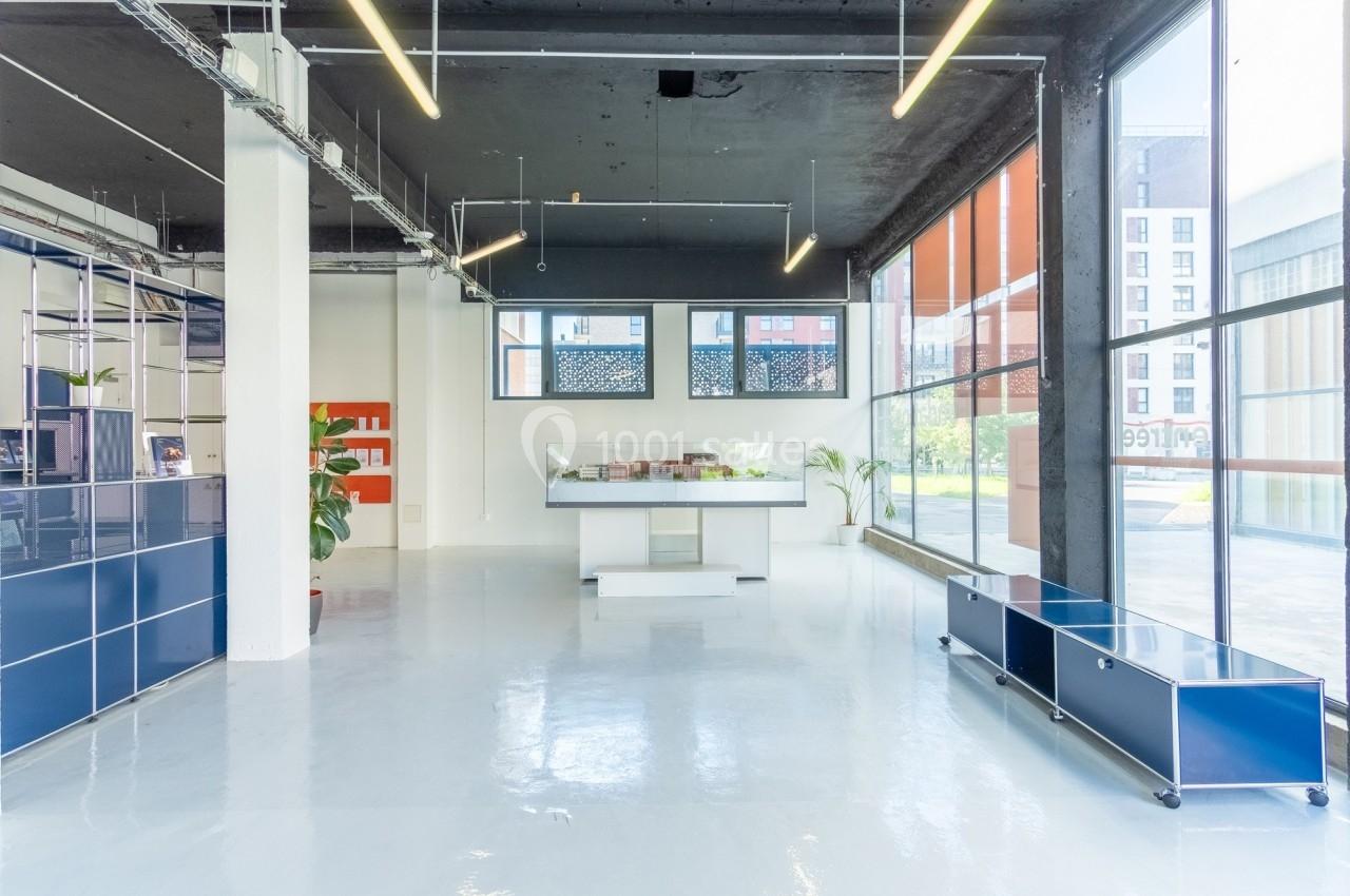 Intérieur lumineux d'un espace moderne avec sol blanc, mobilier minimaliste et grandes baies vitrées.