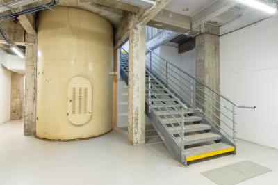 Vue d'un parking vide en extérieur, entouré de bâtiments modernes sous un ciel partiellement nuageux.