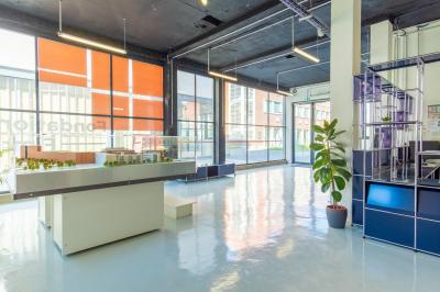 Vue d'un parking vide en extérieur, entouré de bâtiments modernes sous un ciel partiellement nuageux.