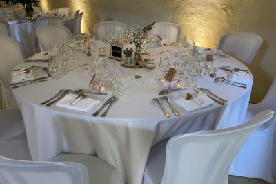 Cuisine rustique avec évier double, plan de travail en inox, réfrigérateur, cuisinière et mur en pierre apparente.