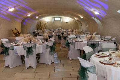 Cuisine rustique avec évier double, plan de travail en inox, réfrigérateur, cuisinière et mur en pierre apparente.