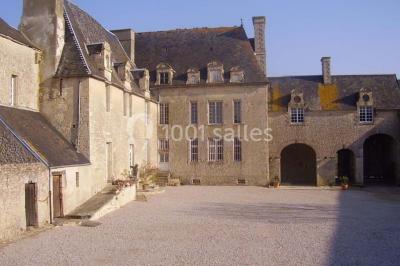 Cuisine rustique avec évier double, plan de travail en inox, réfrigérateur, cuisinière et mur en pierre apparente.