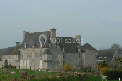 Cuisine rustique avec évier double, plan de travail en inox, réfrigérateur, cuisinière et mur en pierre apparente.