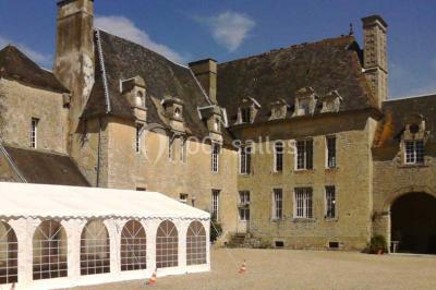 Cuisine rustique avec évier double, plan de travail en inox, réfrigérateur, cuisinière et mur en pierre apparente.