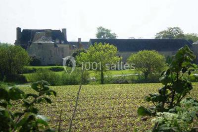 Cuisine rustique avec évier double, plan de travail en inox, réfrigérateur, cuisinière et mur en pierre apparente.