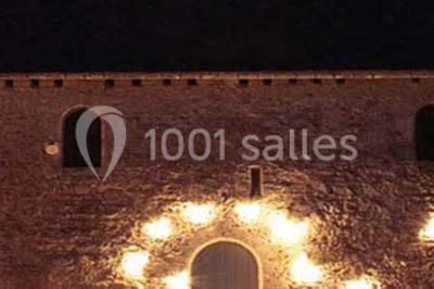 Cuisine rustique avec évier double, plan de travail en inox, réfrigérateur, cuisinière et mur en pierre apparente.