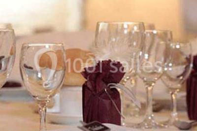 Cuisine rustique avec évier double, plan de travail en inox, réfrigérateur, cuisinière et mur en pierre apparente.