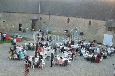 Cuisine rustique avec évier double, plan de travail en inox, réfrigérateur, cuisinière et mur en pierre apparente.