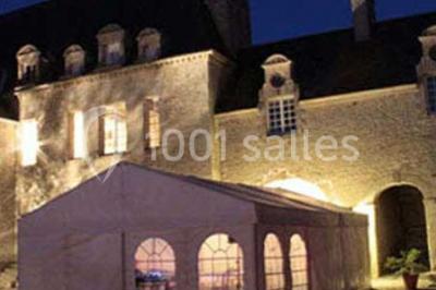 Cuisine rustique avec évier double, plan de travail en inox, réfrigérateur, cuisinière et mur en pierre apparente.