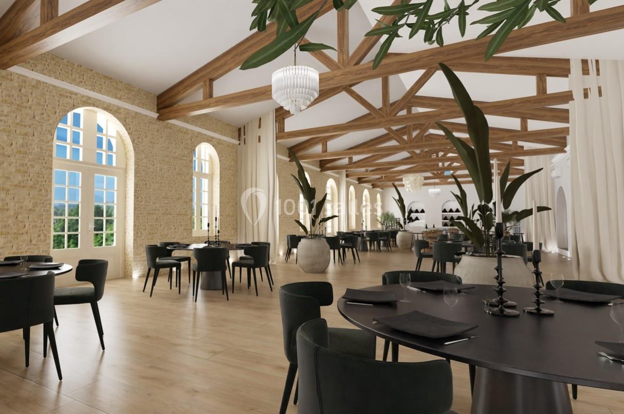 Salle de restaurant lumineuse avec poutres apparentes, grandes fenêtres, tables noires et plantes décoratives.